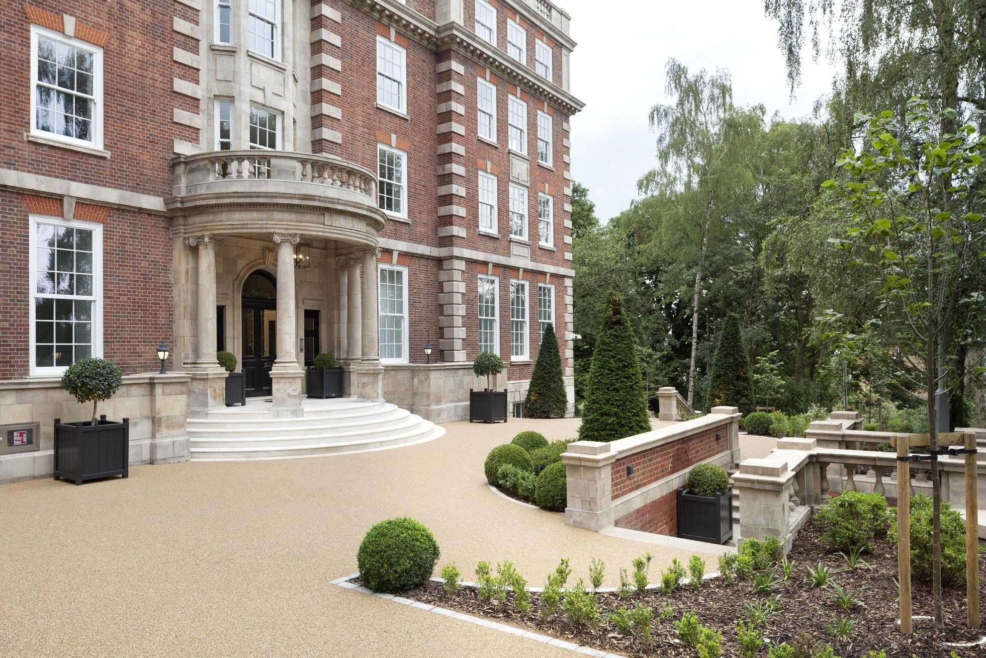 The completed One Highgate elevation with its stone portico, seen across formal gardens.