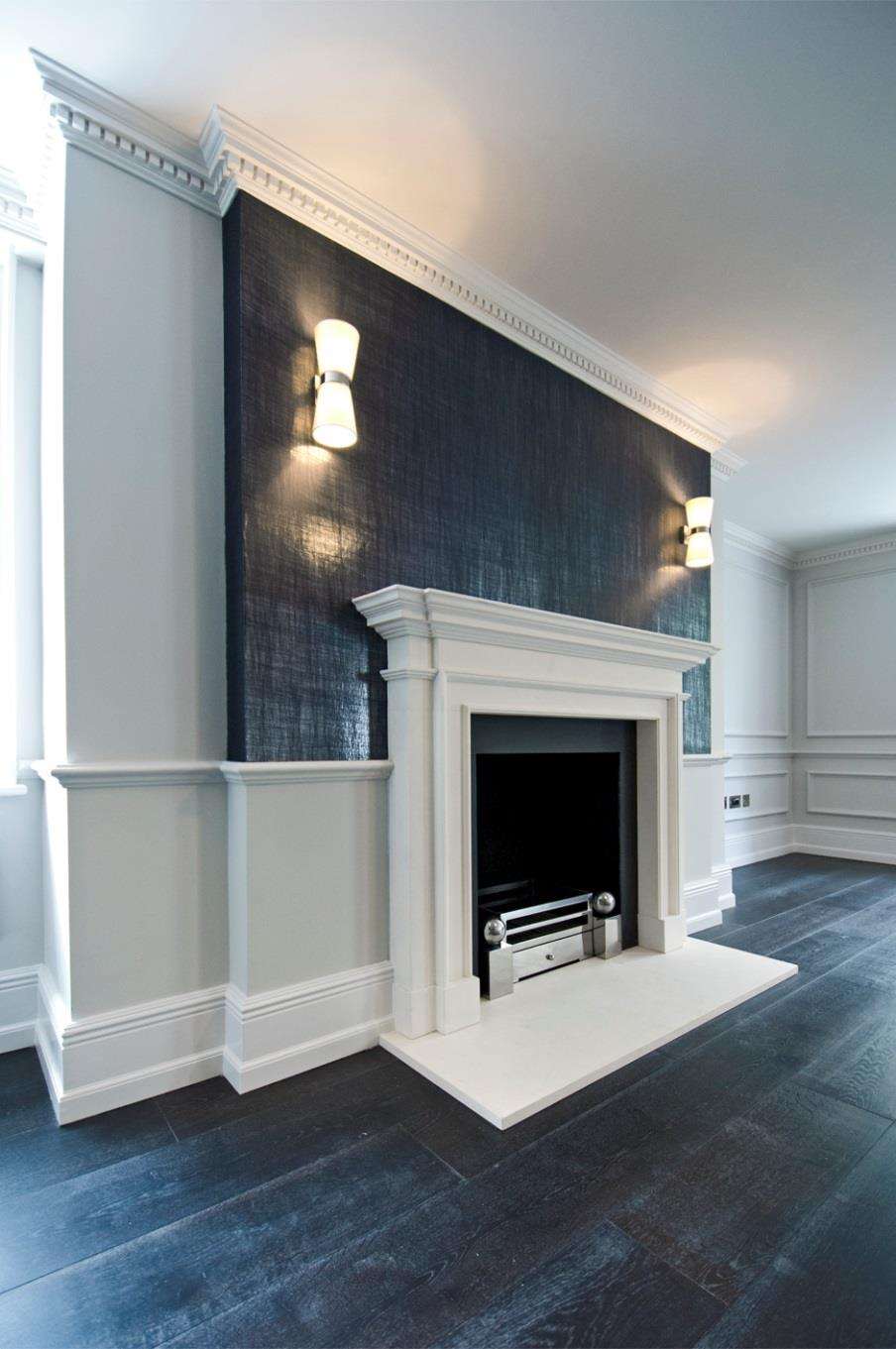 A stone chimneypiece set into dark panelling in a completed Soho Square apartment.