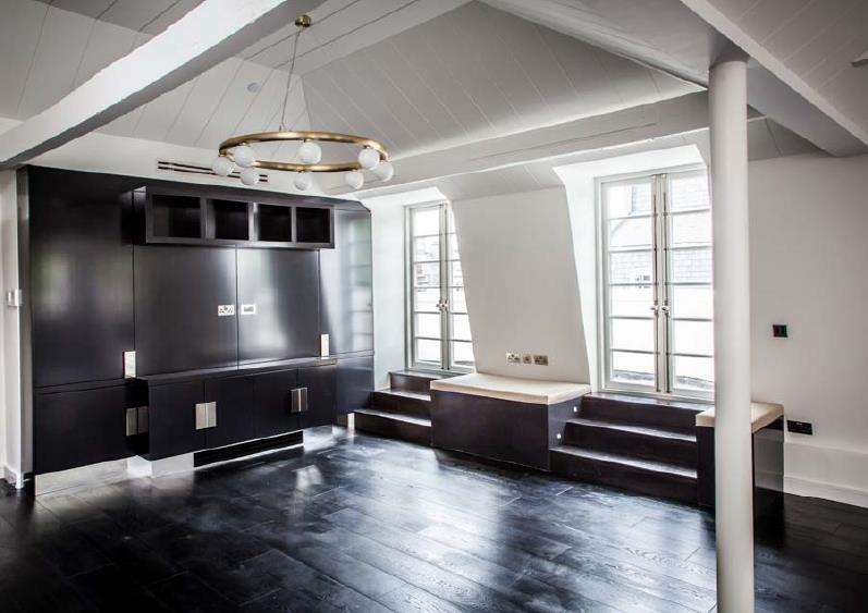 A living room at Soho Square with dark joinery and a fitted media wall.