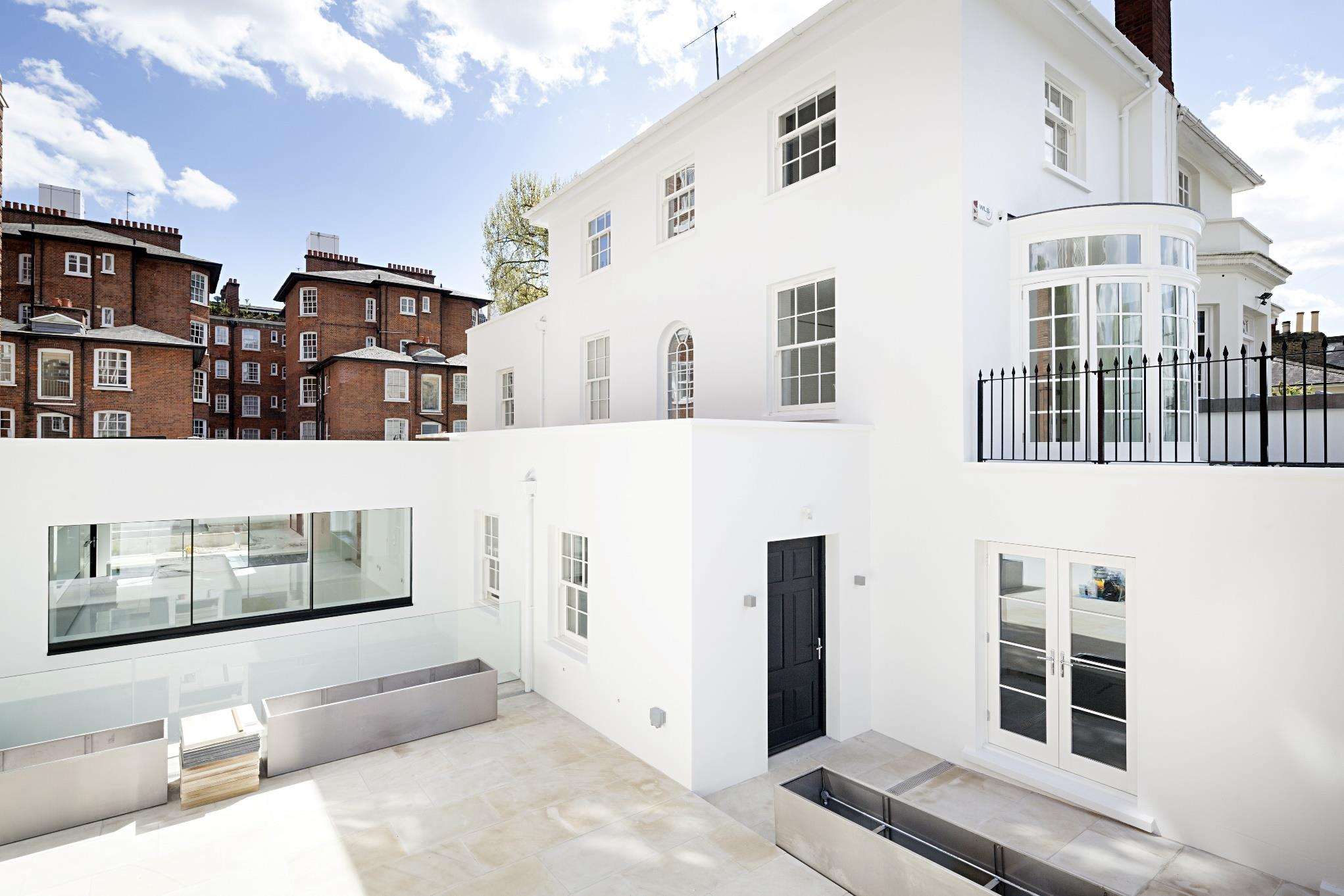 The completed rear elevation at St John’s Wood, white render with full-height glazing.
