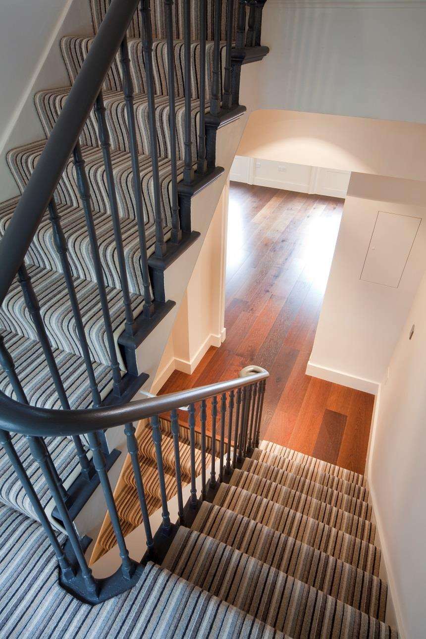 The curved communal staircase at Maddox Street with a wrought balustrade.